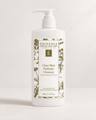 A white pump bottle of Eminence Organic Skin Care Clear Skin Probiotic Cleanser with a white label featuring green botanical illustrations, set against a clean, light beige background.
